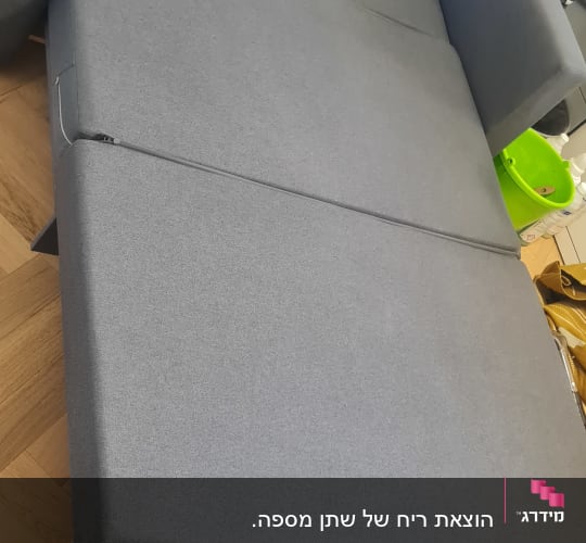 ספה אפורה עם ציוד ניקוי על רצפת עץ